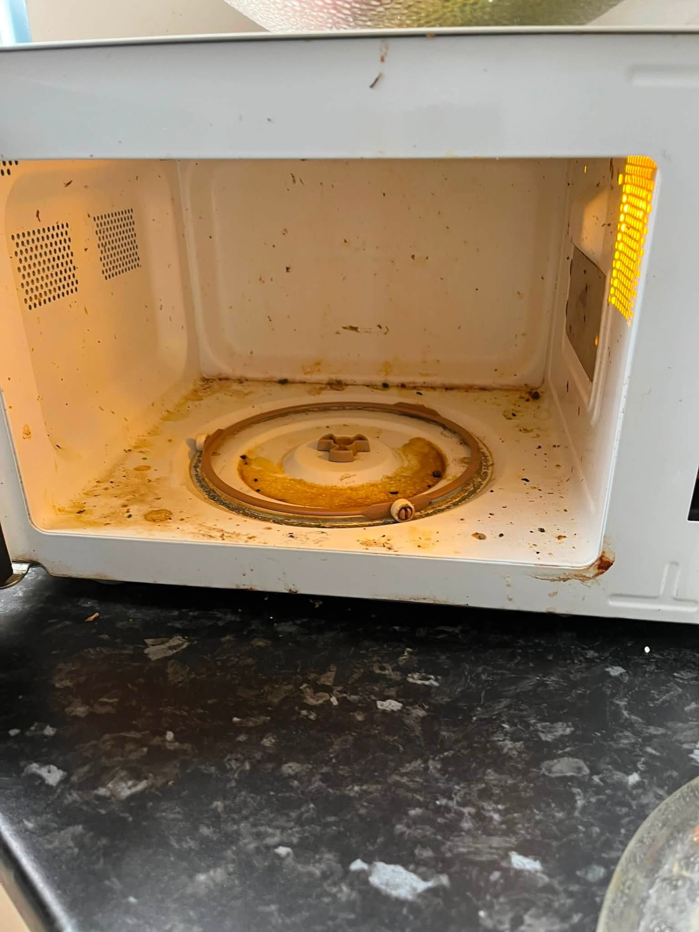 Microwave interior covered in food splatter before cleaning